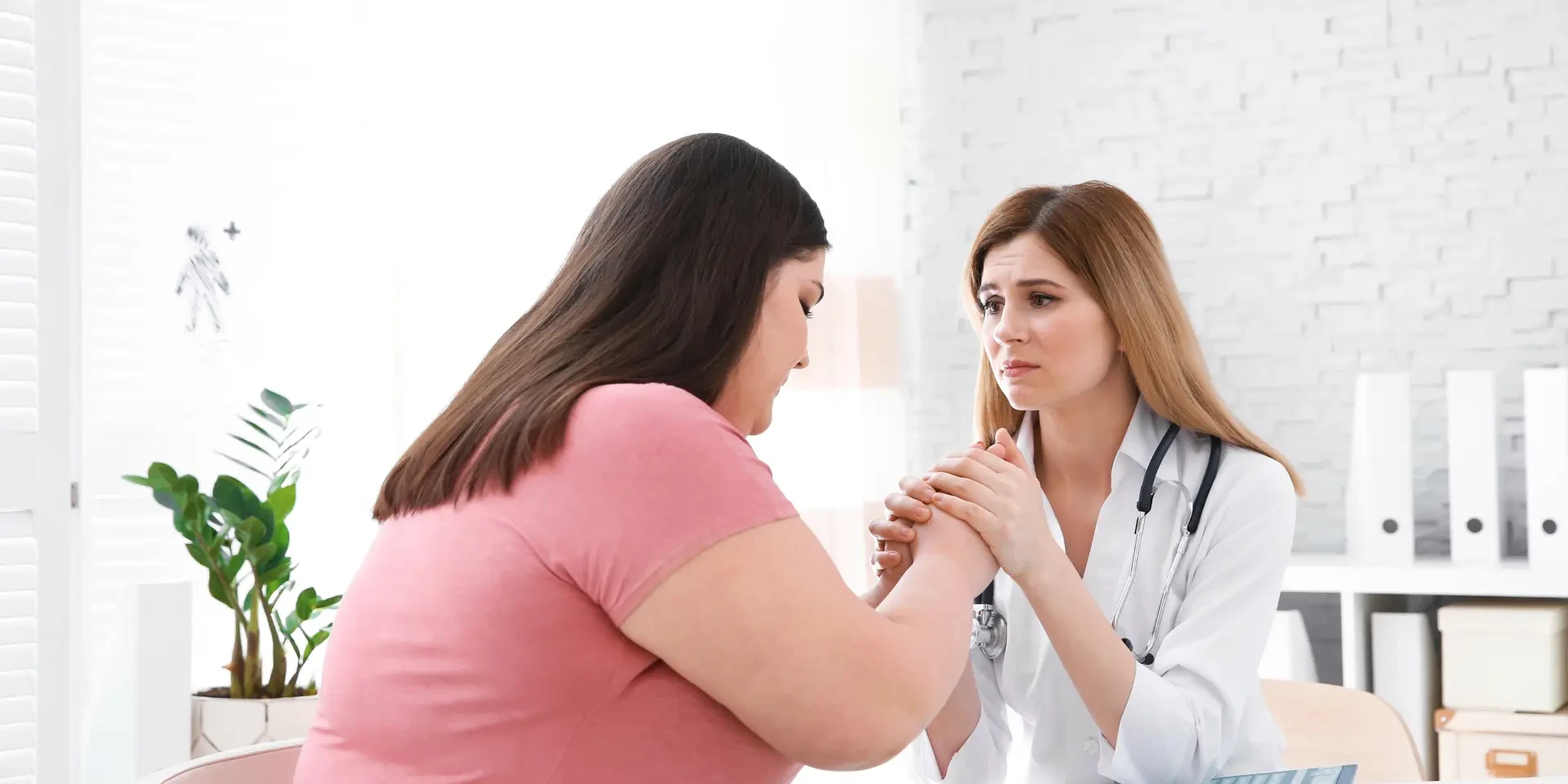 Doctora empática consultando a una paciente con sobrepeso en una clínica luminosa.