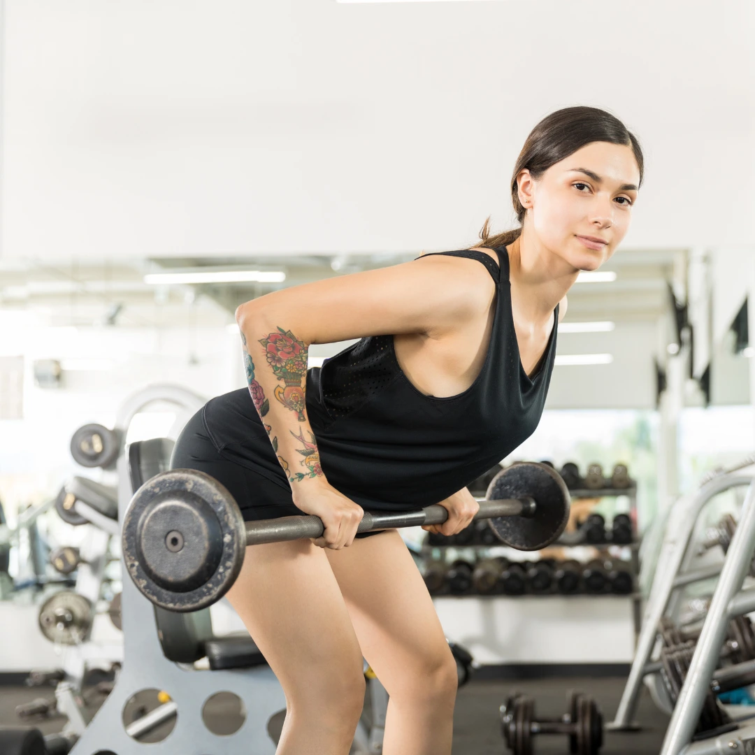 Mujer levantando pesas en el gimnasio, representando confianza y bienestar.
