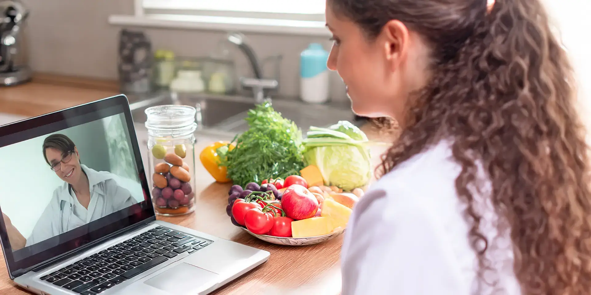 Mujer en consulta virtual con doctora mientras revisa alimentos saludables